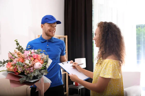 Mujer afroamericana recibiendo ramo de flores del hombre de entrega en el interior —  Fotos de Stock