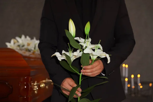 Junger Mann mit weißen Lilien im Bestattungsinstitut, Nahaufnahme — Stockfoto