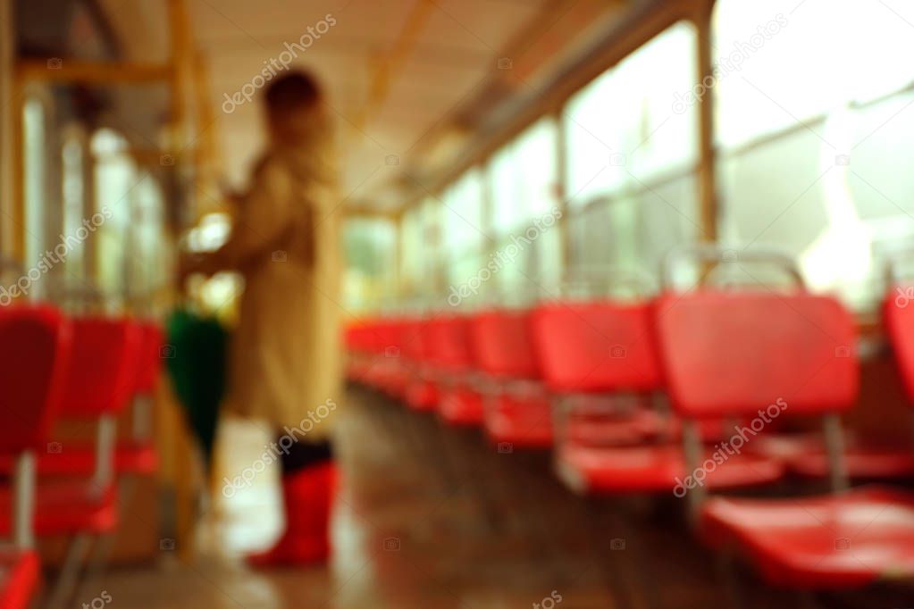 Blurred view of woman with umbrella in tram on rainy day