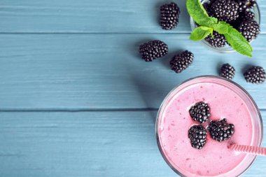 Mavi ahşap arka plan üzerinde lezzetli böğürtlen yüzlü cam ile Düz yatıyordu kompozisyon. Metin için alan