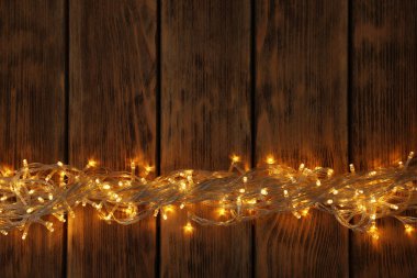 Ahşap arka planda parlayan Noel ışıkları, üst görünüm. Metin için alan