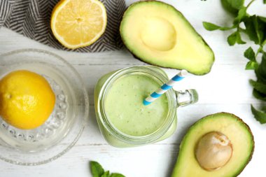 Beyaz ahşap masa üzerinde lezzetli avokado smoothie ile Düz yatıyordu kompozisyon