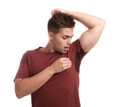 Beyaz arka plana karşı giysilerinde ter lekesi olan genç bir adam. Deodorant kullanma
