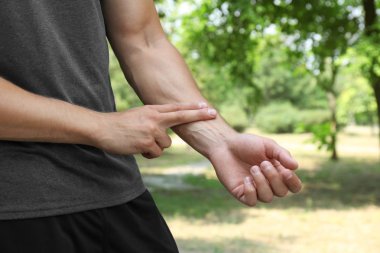 Genç adam açık havada eğitim den sonra nabız kontrol, closeup
