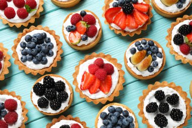 Mavi ahşap masa üzerinde birçok farklı berry tart, düz yatıyordu. Lezzetli hamur işleri