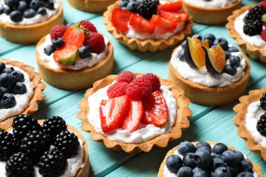 Mavi ahşap masa üzerinde birçok farklı berry tarts. Lezzetli hamur işleri