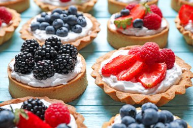 Mavi ahşap masa üzerinde birçok farklı berry tarts. Lezzetli hamur işleri
