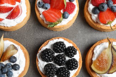 Gri masada farklı berry tart, düz yatıyordu. Lezzetli hamur işleri