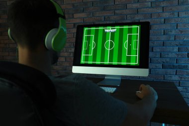 Karanlık odada masada video oyunu oynayan kulaklıklı adam