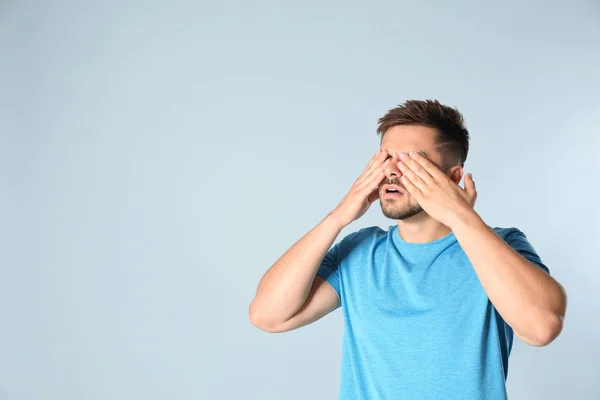 Young man being blinded on grey background, space for text — Stock Photo, Image