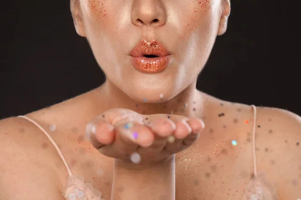 Krásná mladá žena se třpytičkým make-upem na černém pozadí, s výhledem do šatstva — Stock fotografie
