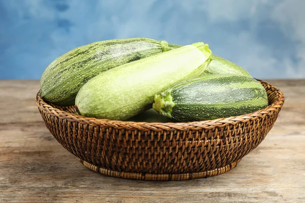 Wicker bowl with fresh ripe green zucchini on wooden table — Stock Photo, Image