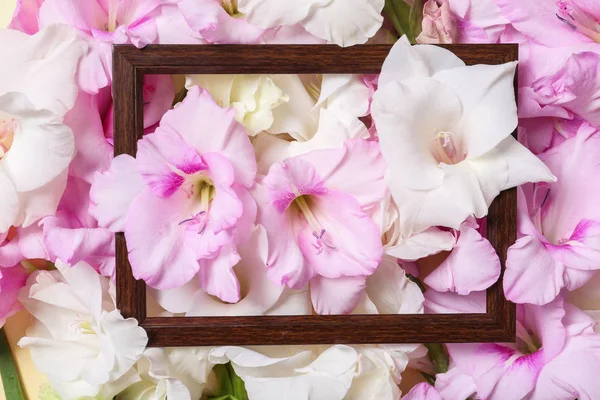 Bovenaanzicht van houten frame en mooie Gladiolus bloemen als achtergrond, close-up — Stockfoto