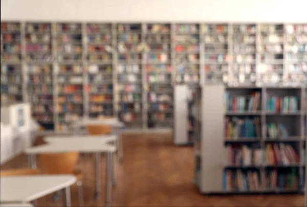 Vista borrosa del interior de la biblioteca con librerías y mesas —  Fotos de Stock