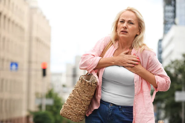 Mature woman suffering from heart attack outdoors. Space for text — Stock Photo, Image