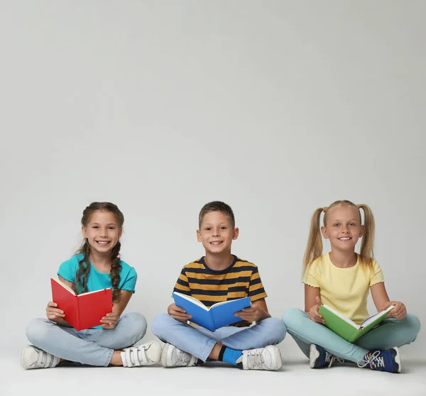 Kleine kinderen lezen boeken over grijze achtergrond — Stockfoto