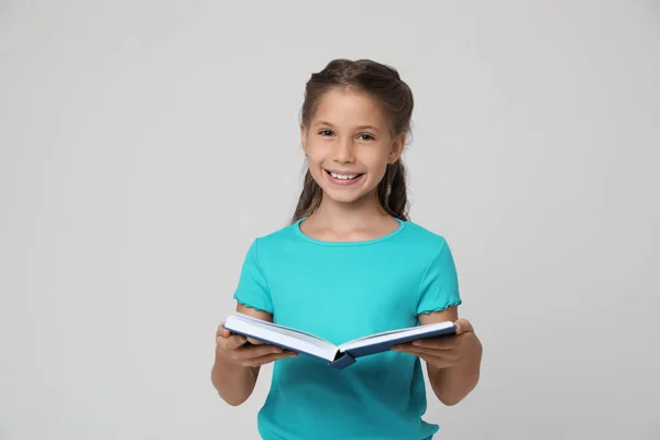 Retrato de linda niña leyendo libro sobre fondo gris — Foto de Stock