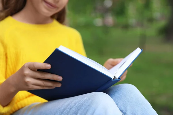 Bonito menina leitura livro no parque verde, close-up — Fotografia de Stock