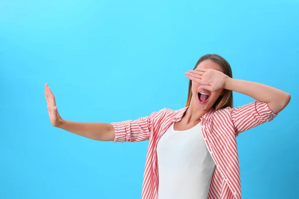 Молодая женщина закрывает глаза руками на синем фоне — стоковое фото