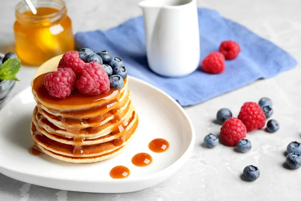 Leckere Pfannkuchen mit frischen Beeren und Sirup auf grauem Tisch — Stockfoto