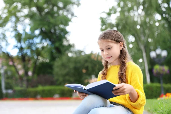 Cute Little Girl czytanie książki w zielonym parku — Zdjęcie stockowe