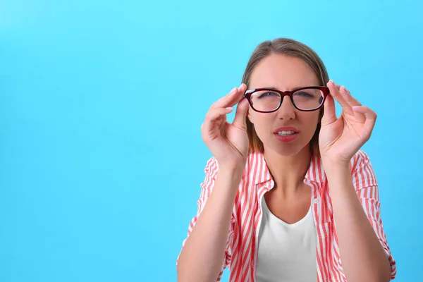 Junge Frau mit Sehschwäche trägt Brille auf blauem Hintergrund — Stockfoto