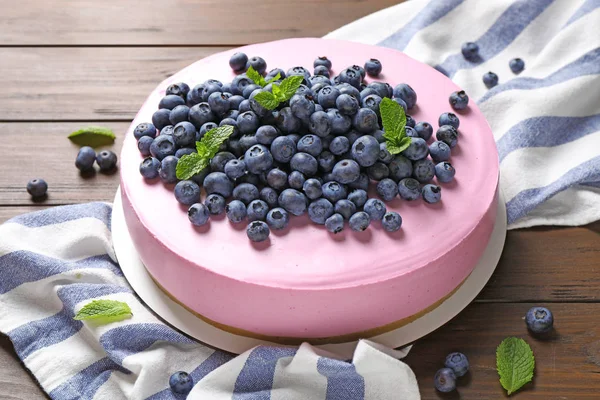 Tasty blueberry cake and napkin on wooden table — Stock Photo, Image