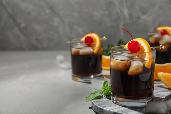 Glas heerlijke cocktail versierd met kersen en sinaasappel op lichtgrijze tafel. Ruimte voor tekst — Stockfoto