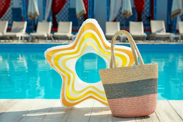 Bolso de playa y anillo inflable cerca de la piscina al aire libre —  Fotos de Stock