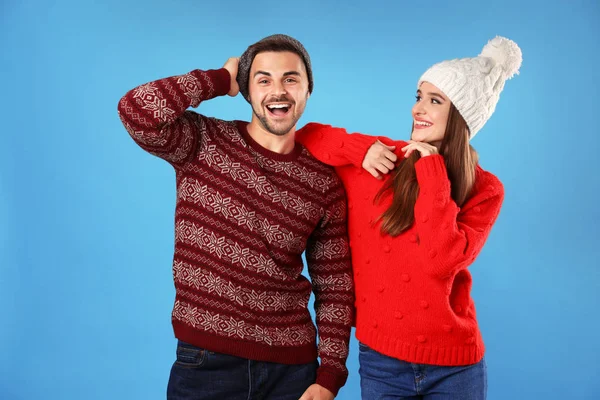 Pareja vistiendo suéteres y sombreros de Navidad sobre fondo azul —  Fotos de Stock