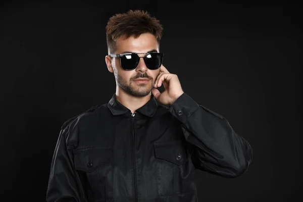 Protetor de segurança masculino em uniforme usando fone de ouvido de rádio em fundo escuro — Fotografia de Stock