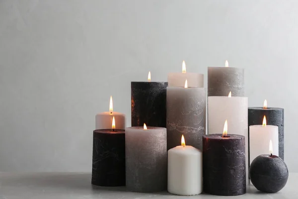 Set of burning candles on table against light background — Stock Photo, Image