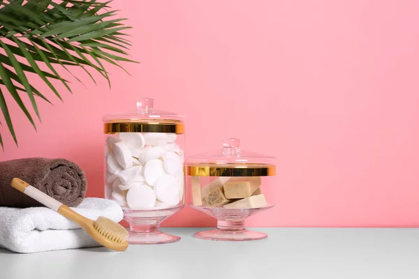 Složení skleněné nádobky s bavlněnými polštářky na stole blízko růžové stěny. Místo pro text — Stock fotografie