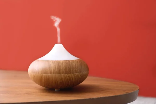 Difusor de aceites esenciales en mesa de madera cerca de la pared roja. Espacio para texto — Foto de Stock