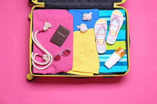Open suitcase with beach objects on pink background, top view — Stock Photo, Image