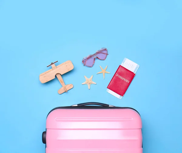 Różowy walizka i obiekty plażowe na niebieskim tle, płaskie lay — Zdjęcie stockowe