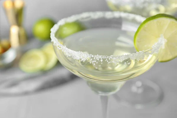 Bicchieri di limone goccia Martini cocktail con fetta di lime sul tavolo contro sfondo grigio, primo piano — Foto Stock