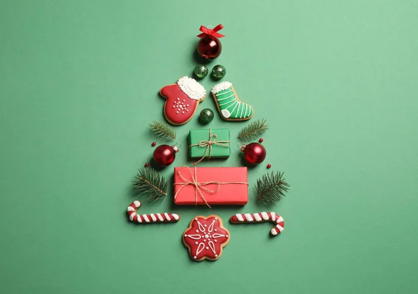 Karácsonyfa sziluettje fenyő ágak és ünnepi dekoráció zöld alapon, lapos feküdt — Stock Fotó