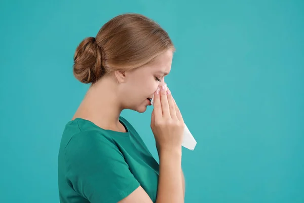 Ung kvinna som lider av allergi mot turkos bakgrund — Stockfoto