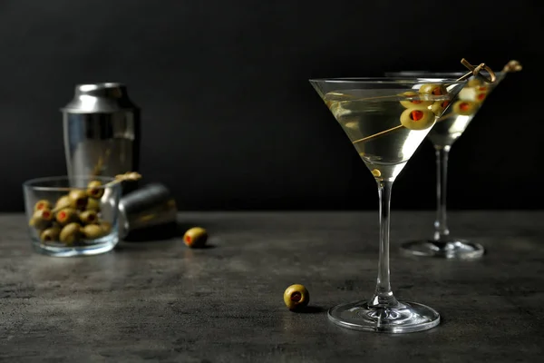 Окуляри класичного сухого мартіні з оливками на сірому столі на чорному тлі — стокове фото