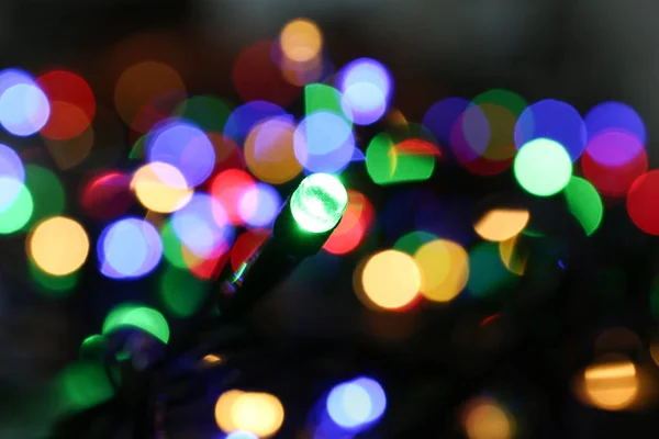 Kolorowe światła świąteczne na ciemnym tle, widok zbliżenie — Zdjęcie stockowe