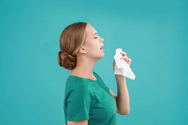 Mujer joven que sufre de alergia sobre fondo turquesa —  Fotos de Stock