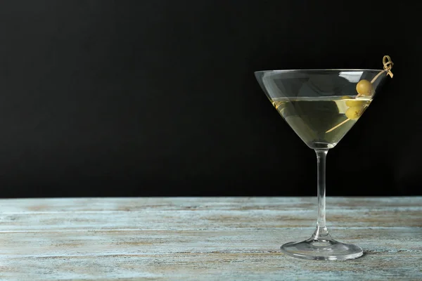 Sklenice klasického suchého Martini s olivami na dřevěném stole na černém pozadí. Mezera pro text — Stock fotografie