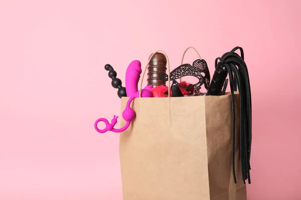 Papieren boodschappentas met verschillende seks speeltjes op roze achtergrond. Ruimte voor tekst — Stockfoto