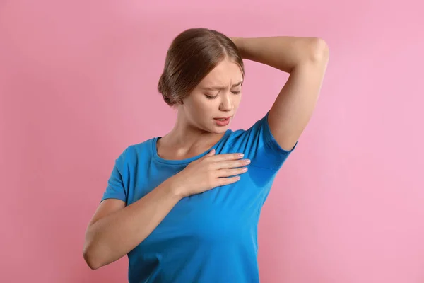 Jonge vrouw met zweet vlek op haar kleren tegen roze achtergrond. Deodorant gebruiken — Stockfoto