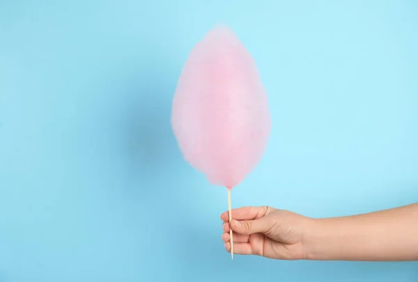 Woman holding sweet pink cotton candy on light blue background, closeup view — Stock Photo, Image