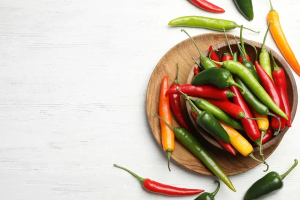 Different chili peppers on white wooden table, flat lay. Space for text