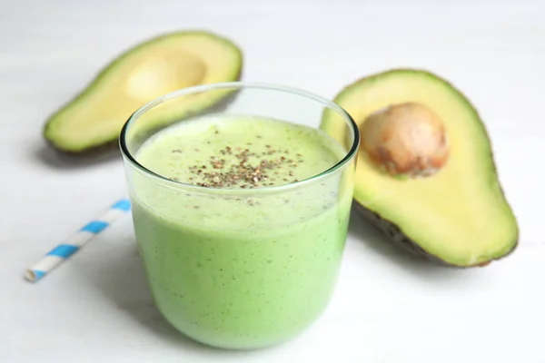 Copo de saboroso smoothie de abacate com sementes de chia na mesa de madeira branca — Fotografia de Stock