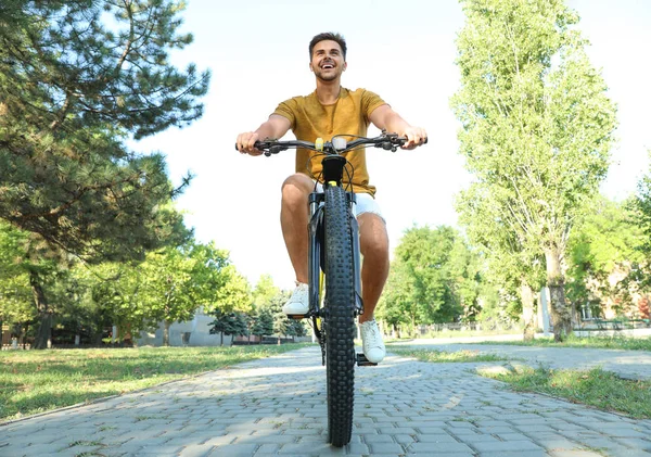 Pohledný mladý muž s bicykl v městském parku, pohled na nízký úhel — Stock fotografie
