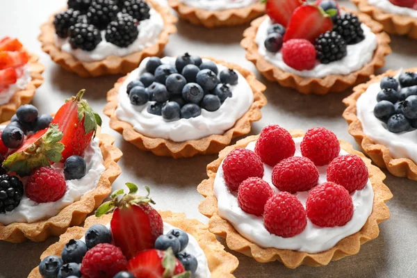 Many different berry tarts on table. Delicious pastries